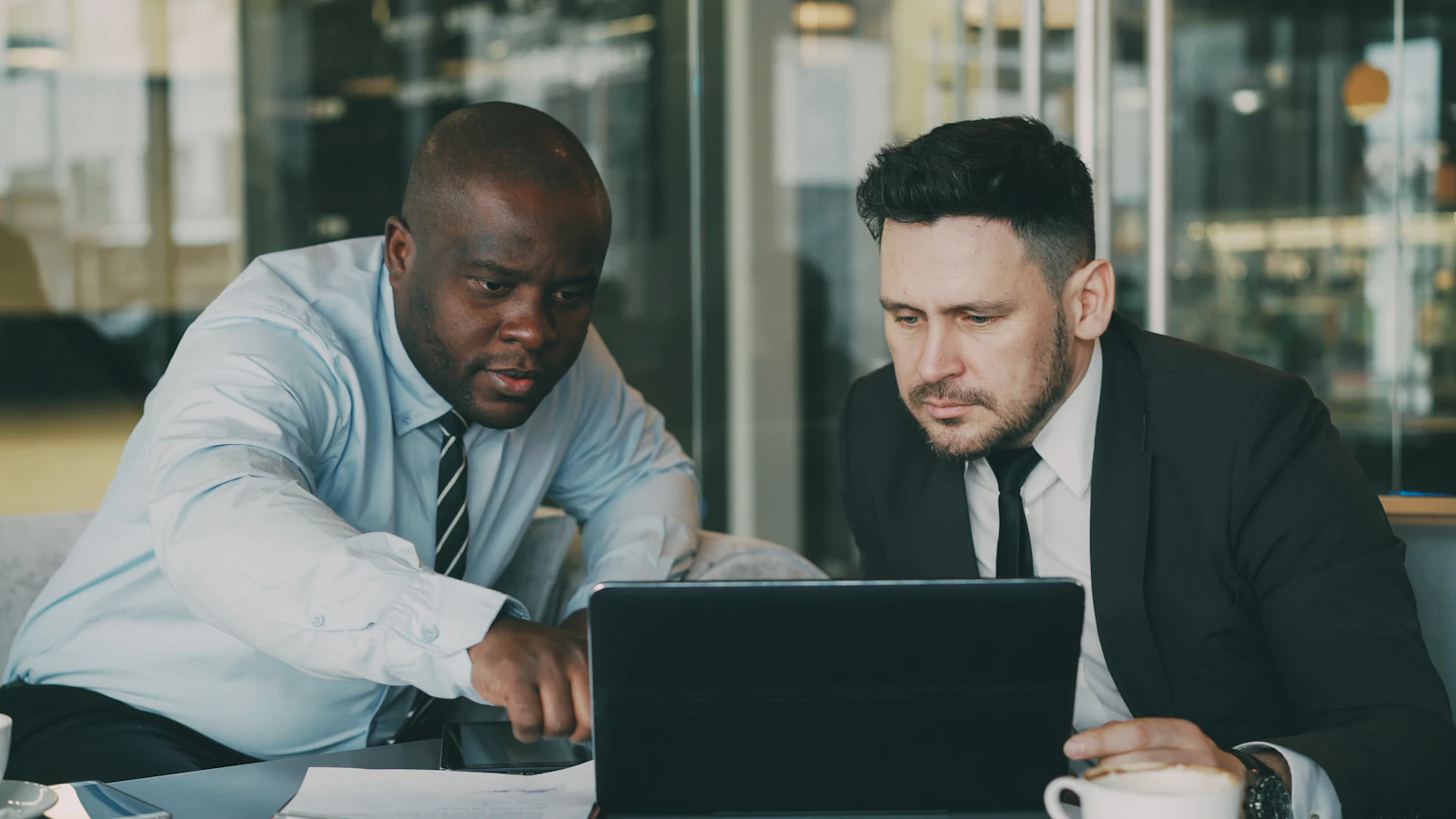 Two colleagues frowning at a laptop in an office